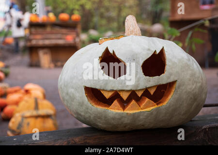 Gespenstisch weiß und orange Halloween Kürbis, Jack O'Lantern an einem hölzernen Tisch Stockfoto