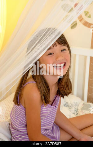 Sieben Jahre alten Mädchen sitzt auf ihrem Bett Stockfoto