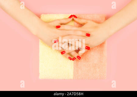 Stilvoll trendy weiblichen Maniküre. Die schöne junge Frau hand mit perfekter rot Maniküre auf rosa Hintergrund. Flach Stil. Stockfoto