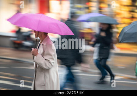 01 November 2019, Hessen, Frankfurt/Main: Menschen Überqueren einer Kreuzung im Stadtteil Bornheim in ständiger Nieselregen (Aufnahme mit Wirkung ziehen). Foto: Frank Rumpenhorst/dpa Stockfoto