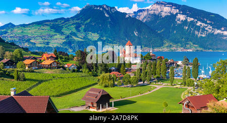 Antenne Panoramablick von Spiez Kirche und Schloss am Ufer des Thunersees im Schweizer Kanton Bern bei Sonnenuntergang, Spiez, Schweiz. Stockfoto