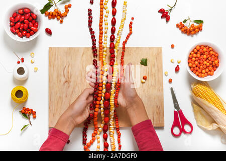 Viele farbenfrohe Handgefertigte Ketten aus verschiedenen Beeren und Samen in der Hand des Kindes. Stockfoto