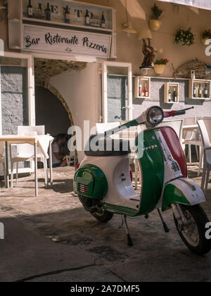 Vespa Motorrad in den Farben der italienischen Flagge vor der traditionellen Restaurant und Pizzeria mit Schriftzug in Tropea, Kalabrien, Italien Stockfoto