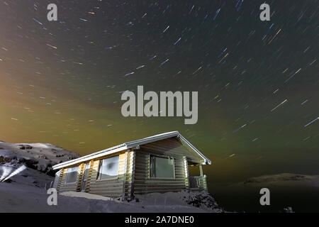 Spuren von Stars und Aurora über ein Holzhaus und die Barentssee Teriberka, Region Murmansk, Kola Halbinsel. Russland. Lange Belichtung Foto Stockfoto