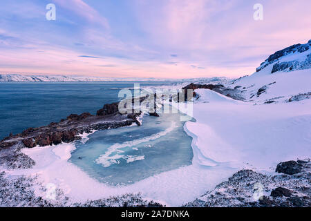 Einen kleinen zugefrorenen See und die Barentssee Küste. Teriberka, Region Murmansk, Kola Halbinsel. Russland. Schwerpunkt auf dem zugefrorenen See. Stockfoto