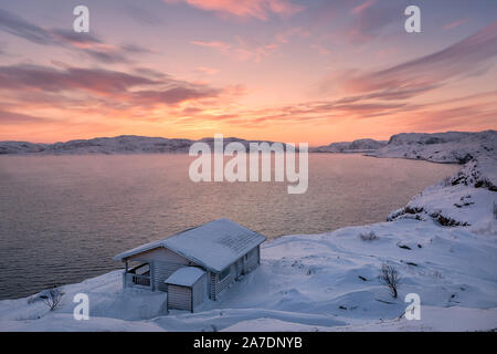 Ein Holzhaus, Barentssee bei Sonnenaufgang in Teriberka, Region Murmansk, Kola Halbinsel. Russland. Stockfoto