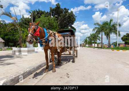 Ciego de Avila, Kuba. Pferdekutsche in einer Straße mit einer kleinen kubanischen Stadt während einer bewölkt und sonnig Sommertag. Stockfoto