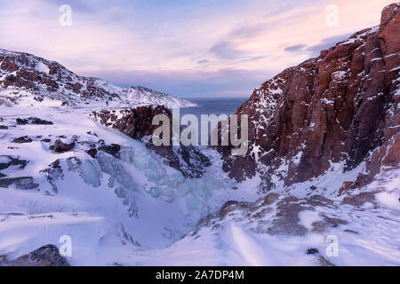 Nahaufnahme Foto einen gefrorenen Wasserfall bei Sonnenuntergang. Die Küste der Barentssee. Teriberka, Region Murmansk, Kola Halbinsel. Russland Stockfoto