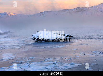 Metall und Holz- Teile der alten Schiff Thunfischwadenfänger auf der Barentssee Küste bei Sonnenaufgang. Teriberka, Region Murmansk. Russland. Weiches Licht mit Meer Rauch Stockfoto