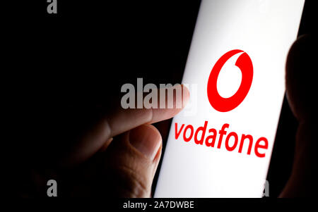 Vodafone Logo auf einem Bildschirm des Smartphones in einem dunklen Raum und einen Finger zu berühren. Stockfoto