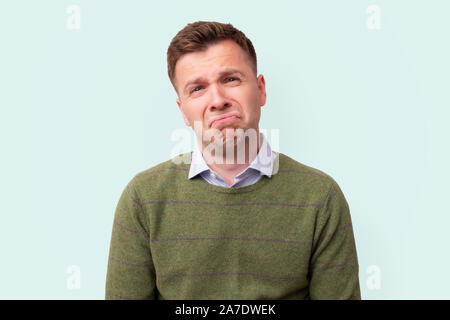 Traurig und unglücklich, junger Mann im grünen Pullover auf Kamera. Studio shot Stockfoto