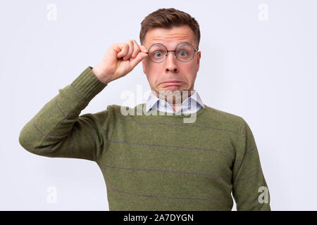 Junge männliche Kursteilnehmer holding Gläser werden an Ihrem Angebot interessiert. isolierte Studio auf farbigem Hintergrund Stockfoto