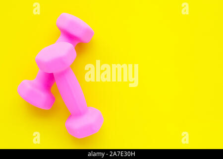 Blick von oben auf die rosa Hanteln auf gelbem Hintergrund. Platz kopieren Stockfoto
