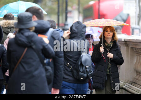 London, Großbritannien. 1 Nov, 2019. Eine Frau, die Schutz vor dem Regen unter einem Dach an einem regnerischen Tag. 70 mm Regen wie in Großbritannien klammern für schwere Duschen und Gale force Winde dieses Wochenende erwartet. Quelle: Steve Taylor/SOPA Images/ZUMA Draht/Alamy leben Nachrichten Stockfoto