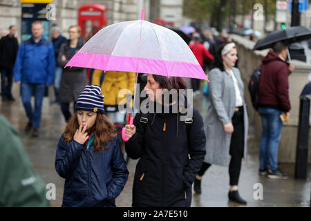 London, Großbritannien. 1 Nov, 2019. Eine Frau, die Schutz vor dem Regen unter einem Dach an einem regnerischen Tag. 70 mm Regen wie in Großbritannien klammern für schwere Duschen und Gale force Winde dieses Wochenende erwartet. Quelle: Steve Taylor/SOPA Images/ZUMA Draht/Alamy leben Nachrichten Stockfoto