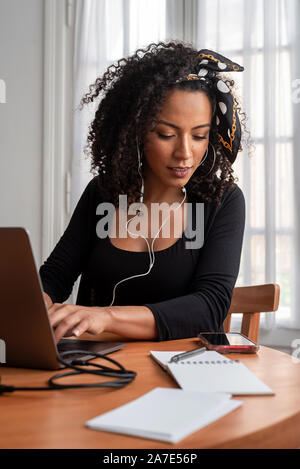 Schuss der jungen Latin Frau zu Hause mit Laptop und Unterlagen arbeiten Stockfoto