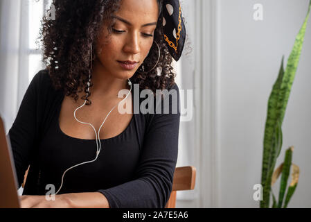 Schuss der jungen Latin Frau zu Hause mit Laptop und Unterlagen arbeiten Stockfoto