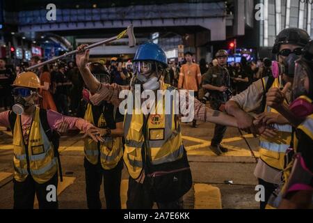 Eine Gruppe von Menschenrechtsaktivisten halten Hände während der Halloween in Hongkong. Demonstranten weiterhin für Hong Kong's Chief Executive Carrie Lam zu nennen ihre übrigen Forderungen zu erfüllen, da die umstrittene Auslieferung Rechnung zurückgenommen wurde, zu der auch eine unabhängige Untersuchung über die Brutalität der Polizei, der Rückzug des Wortes 'Riot' die Kundgebungen zu beschreiben, und das allgemeine Wahlrecht. Stockfoto