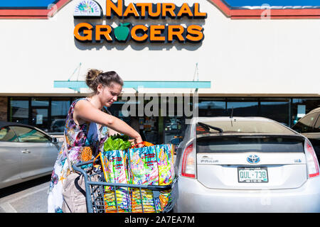 Durango, USA - 22. August 2019: Frau Einkaufen mit Warenkorb und Taschen mit Vorzeichen vor dem Eingang zu den natürlichen Lebensmittelgeschäft von Parkplatz in Colorado Stockfoto