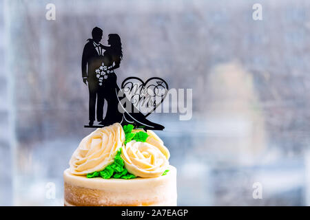 New York City, USA - April 7, 2018: Nahaufnahme von tiered Vanille goldenen Licht weiß gelb Creme Hochzeitstorte mit paar Zeichen Dekoration Topper stand gr Stockfoto