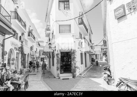 Skiatthos Griechenland - 31. Juli 2019; Skiathos street scene in Schwarzweiß. mit Menschen frühstücken und zu Fuß entlang der engen Gassen. Stockfoto