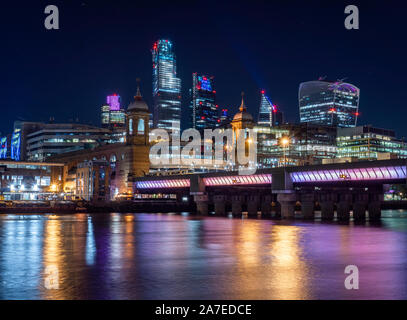 Skyline von London bei Nacht einschließlich beleuchtete Brücke über die Themse und die Stadt London im Hintergrund Stockfoto