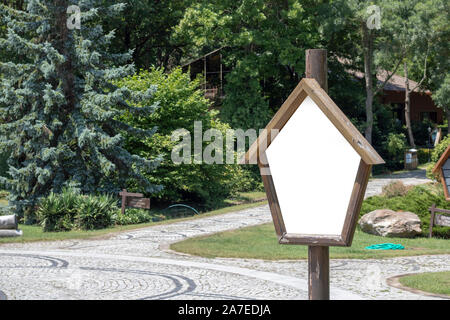 Holz- punkt-Schild am grünen Garten in ein kleines Dorf. Aus basalt Platten ebnet. Stockfoto