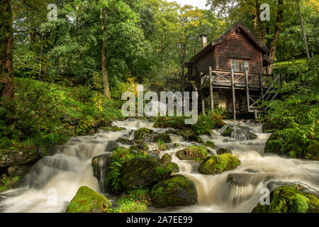 Alte Wassermühle in einem grünen Wald mit einem plätschernden Fluss. Schuss mit langsamen Shutterspeed geben einen unscharfen waterstream. Sommer mit Sonnenschein. Stockfoto