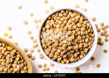 Linsen in kleinen Keramik Teller mit verstreuten Samen auf weißem Hintergrund. Stockfoto