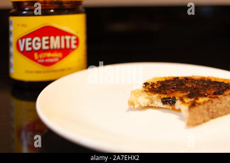 Sydney, Australien - 2 November, 2019 - Vegemite Toast und Butter auf sauerteig mit Biss mit Vegemite jar im Hintergrund. Ein klassisches Symbol Stockfoto