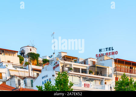 SKIATHOS GRIECHENLAND - 31. JULI 2019; Gebäude tiered bis Griechische Insel Hang mit alten Hotel San Remo unterzeichnen und eine Windmühle Stockfoto