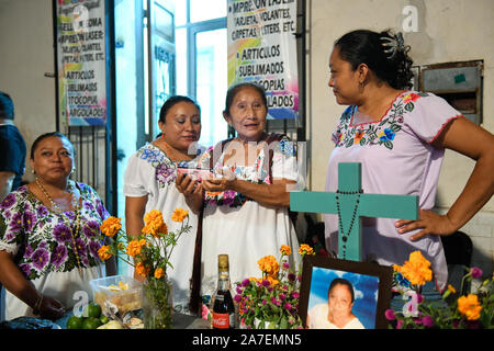 Merida Frauen mit Handy vor ihrer Familie Altar während Hanal Pixan ist die Feier des Tages der Toten, die von der Maya-kultur stammt. Merida, Yucatan, Mexiko. Stockfoto