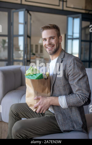 Mann im Wohnzimmer sitzen nach zum Supermarkt gehen Stockfoto
