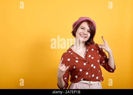 Junge schöne Brünette Frau Lächeln und Lachen tun Rock Symbol Stockfoto