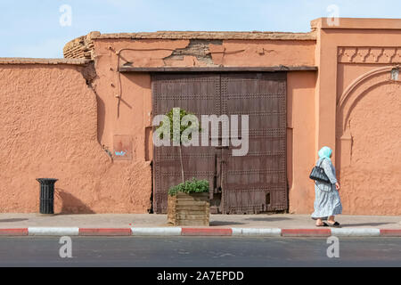 Arabische Frau und Holztür in der Stadt Marrakesch. Marokko Oktober 2019 Stockfoto