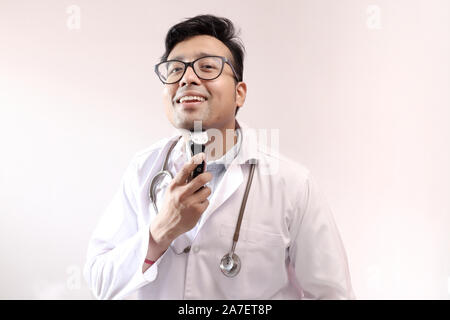 Männliche indische Arzt im weißen Kittel und Stethoskop trimmen Bart Trimmer. Arzt styling Thema Bild Stockfoto