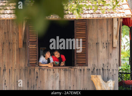 Vietnam Phu Quoc Island 2. April 2019. Zwei Kellnerin Mädchen vorsichtig aus dem offenen Fenster des Cafe aus der Verbrennung in der Luft Stockfoto