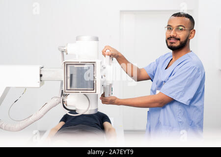 Erfolgreiche junge Arzt in der blauen Uniform und Brillen mit neuer Ausrüstung Stockfoto