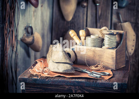 Nahaufnahme von Schuster Arbeitsplatz mit Tools, Schuhe und Schnürsenkel Stockfoto