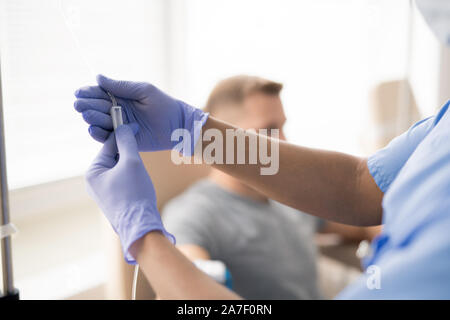 Hände von Behandschuhten Arzt holding Teil der dropper mit Medizin für einen Patienten Stockfoto