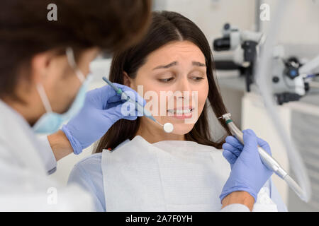 Angst Frau an zahnmedizinischen Büro, panickly an den zahnmedizinischen Tools suchen Stockfoto