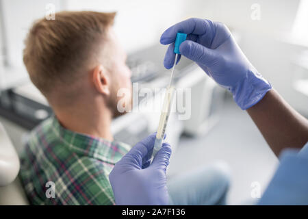 Behandschuhten Arzt kleine Dropper und halten Sie in Kolben mit Medizin Stockfoto