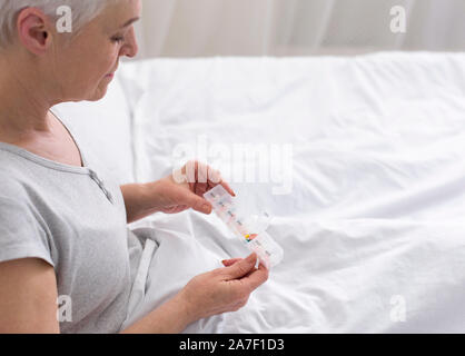 Ältere Dame, die Pillen aus medizinischen, im Bett sitzen Stockfoto