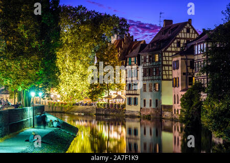 Junge Menschen genießen Sie den Kanal in der Nacht in der Petite France Viertels in Straßburg, Frankreich, gegenüber der Fachwerkhäuser im Wasser widerspiegelt. Stockfoto