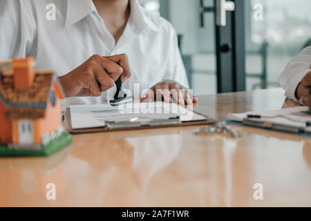 Real estate agent mit stamper Für das Stempeln auf Hypotheken darlehen Vertrag genehmigte Dokument Stockfoto