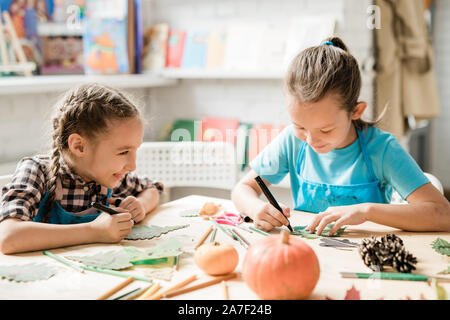 Zwei fröhliche Schülerinnen sitzen, Schreibtisch und Weihnachtsschmuck Stockfoto