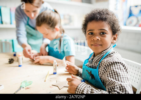 Cute Schüler in der blauen Schürze Vorbereitung handgefertigte Karton Halloween Dekorationen Stockfoto