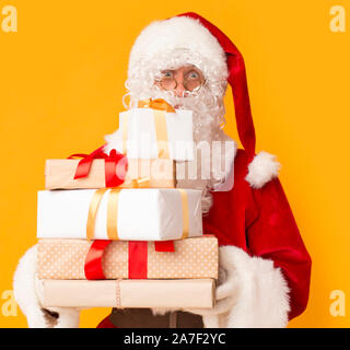 Santa mit den derzeitigen Boxen für Kinder auf Orange Stockfoto
