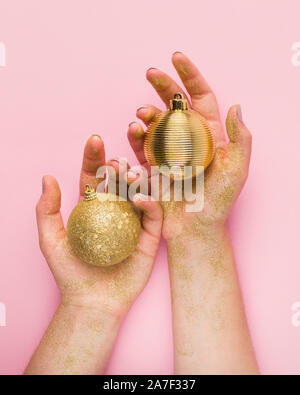 Nahaufnahme von Frau Hände mit goldenen Kugeln auf rosa Hintergrund Stockfoto