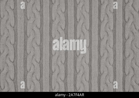 Strickwaren Stoff Textur mit Zöpfen und Streifen. Wiederholung der Maschine Stricken Textur der Pullover. Grau gestrickt Hintergrund. Stockfoto